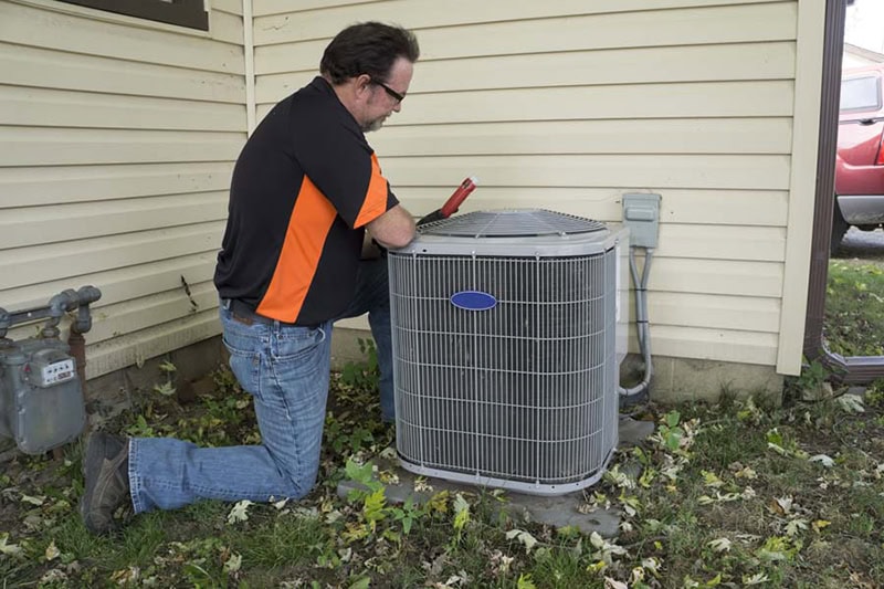 3 Signs It’s Time for a New AC. Tech with AC unit.